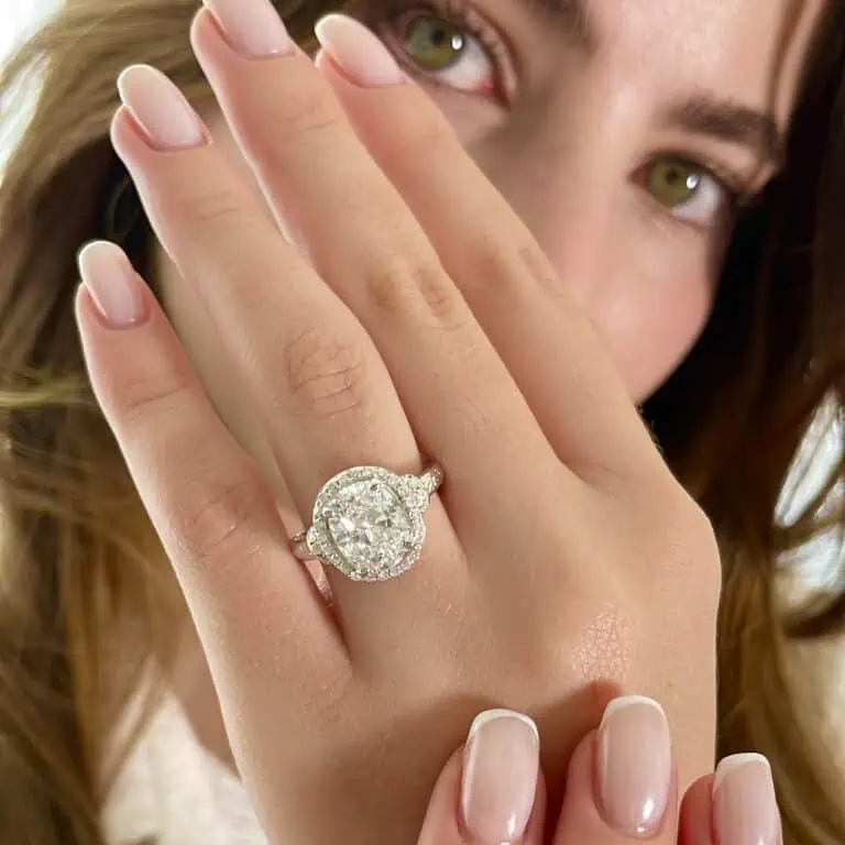 a woman shows oval halo engagement rings on finger